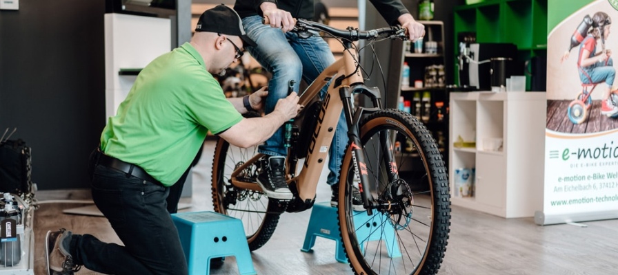Ein Service-Mitarbeiter der e-motion e-Bike Welt stellt einem Kunden das e-Bike korrekt ein